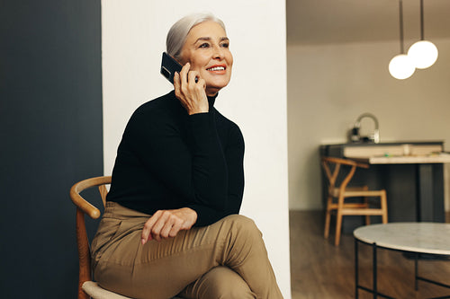 Mature and professional woman speaking on the phone in home office