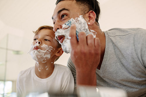 Funny father and son shaving in bathroom