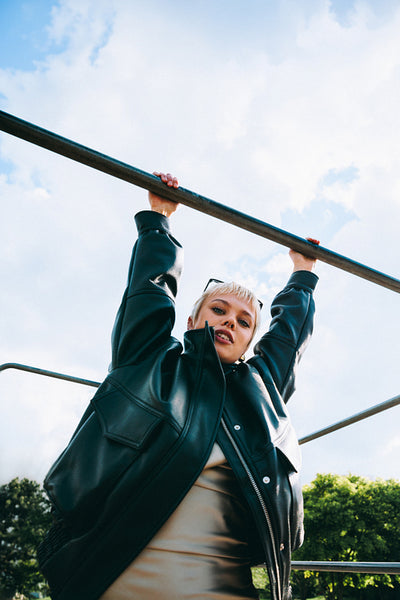Woman hangs from a bar outdoors at a playground
