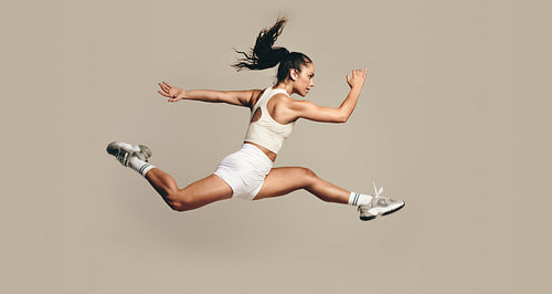Active female athlete running mid air in a vigorous trining session