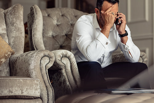 Stressed businessman talking on phone from hotel room
