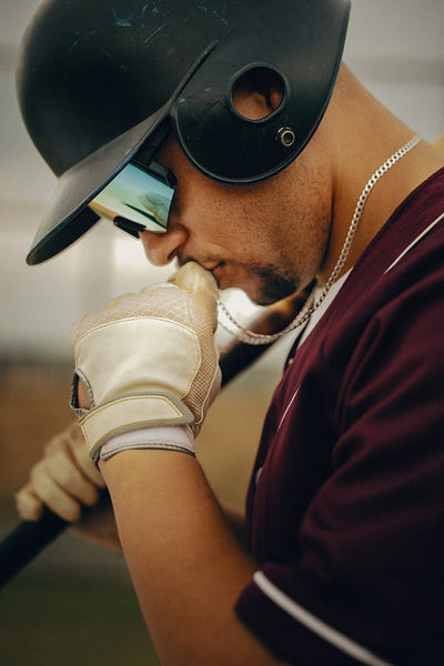 Baseball player kissing necklace for good luck, embodying a charming ritual before game