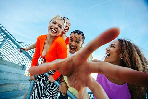 Young friends lean toward the camera and laugh by the waterfront