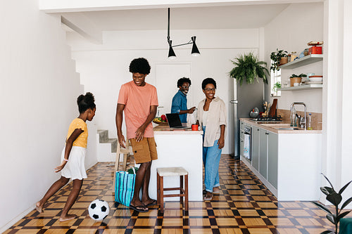 Siblings playing with a soccer ball in a Brazilian kitchen, enjoying family time