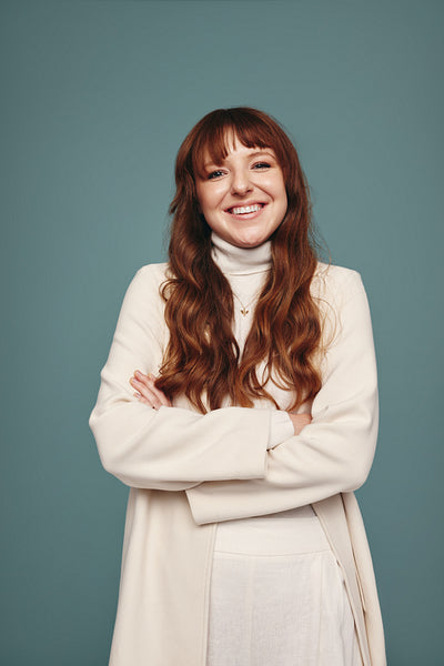 Carefree young woman smiling with her arms crossed