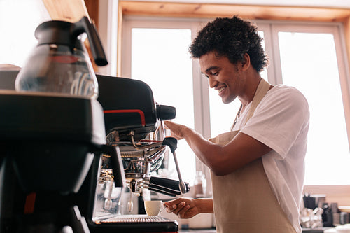 Young man making coffee with an espresso coffee machine at cafe