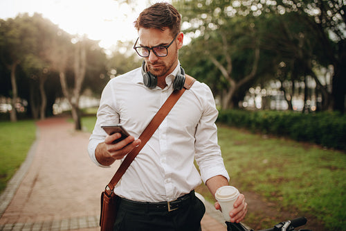 Businessman checking his mobile phone standing in a park