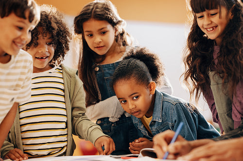 Kids learning from their teacher in school. Group of children pay attention in class