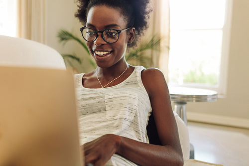 Happy woman relaxing on sofa using laptop