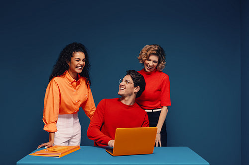 Team of coworkers brainstorming together with laptop in bold colors