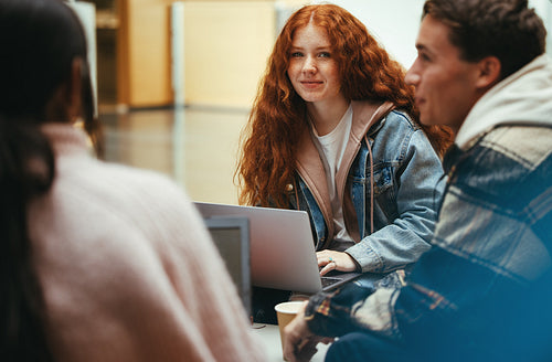 Girl sitting with classmates in college lobby