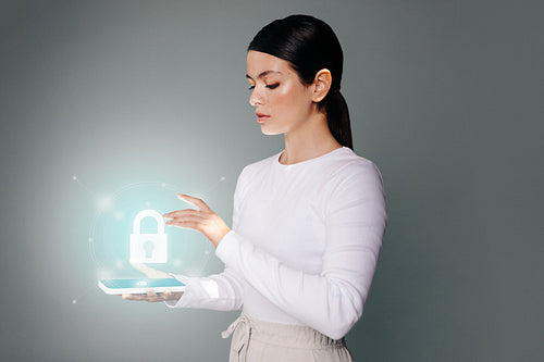 Woman unlocking her smartphone using fingerprint authentication in a studio