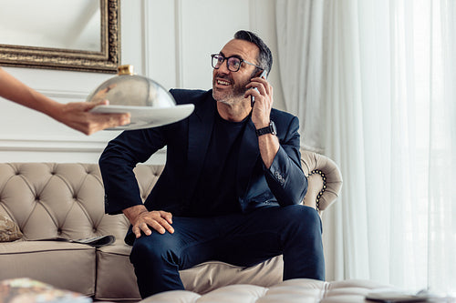 Waiter serving food to businessman in hotel room
