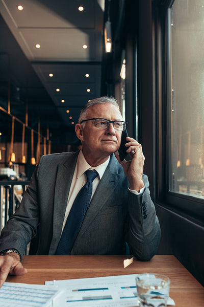 Senior businessman sitting at cafe making a phone call