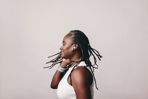 Woman with dreadlocks listening to music on wireless earbuds