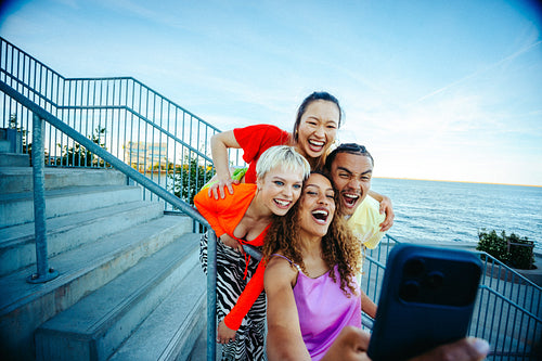 Stairs frame friends taking a selfie with a smartphone by the waterfront