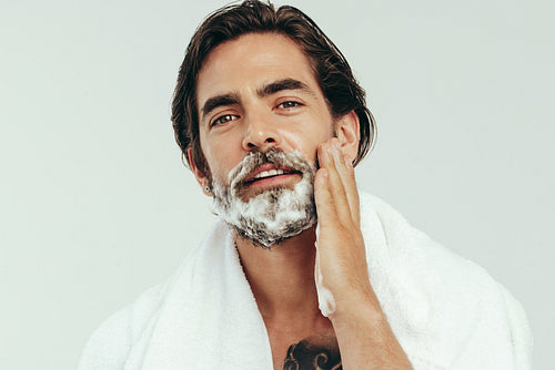 Man applying shaving cream to his facial hair before a shave
