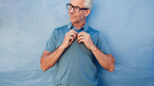 Handsome mature man buttoning up his tshirt