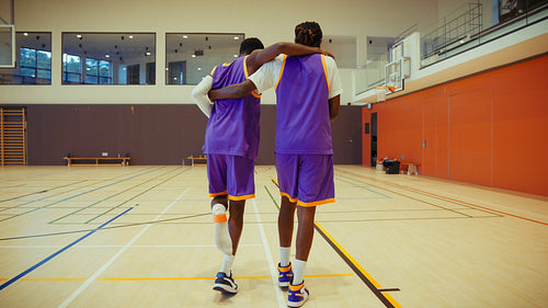 Injured basketball player supported by teammate