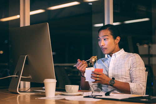 Asian businessman having dinner while working late in office