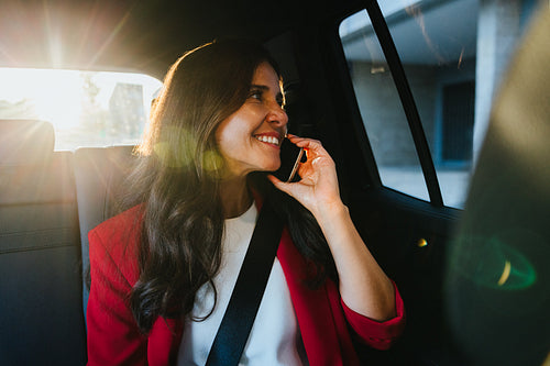 Smiling businesswoman having a phone call inside a car