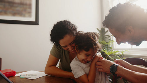 Family fun on a homeschool break: Mother and father tickle their son in a playful moment