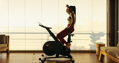 Sweaty black female exercising on indoor cycling bike