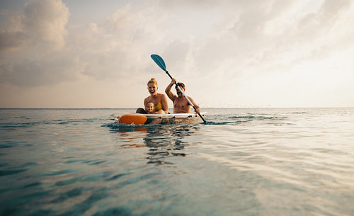 Man and woman rowing a canoe on a serene lake with a young child, enjoying a beautiful water adventure.