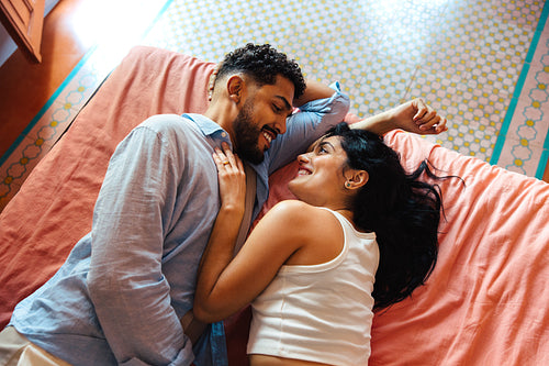 Young couple lying together on a bed and sharing a joyful moment