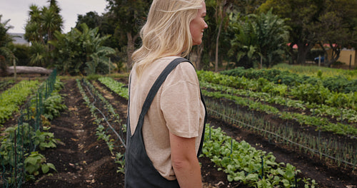 Cheerful organic farmer walking around her vegetable garden