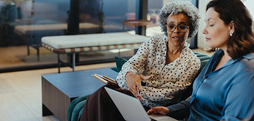 The office business meeting shows women collaborating on a laptop together