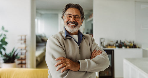 Senior man smiling with crossed arms at home