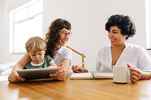 Smiling female couple with son using tablet pc