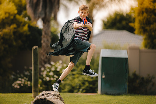 Boy pretending to be superhero fighting with toy gun