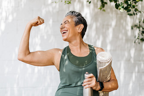 Elderly woman celebrates her fitness achievements by flaunting her bicep outdoors