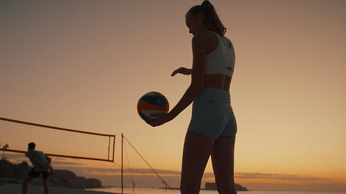 Professional beach volleyball player dusts off ball as the sun sets