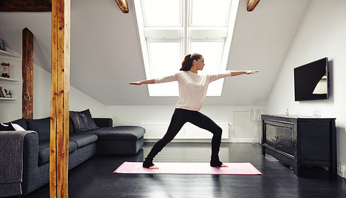 Attractive young woman doing yoga at home