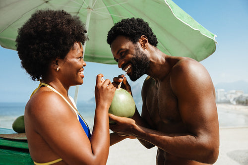 Smiling couple enjoying coconut drink on beach vacation