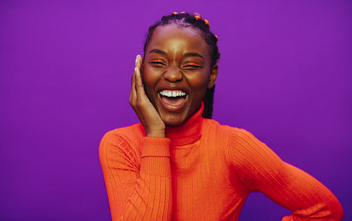 Cheerful young woman with stylish braided hair and vibrant purple background