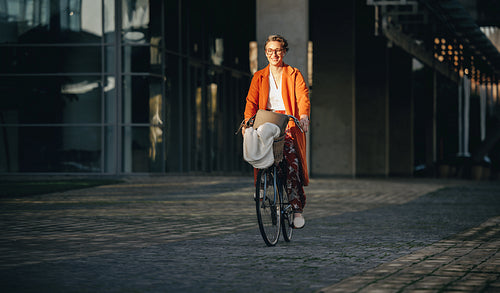 Happy business woman riding a bicycle to work in the city