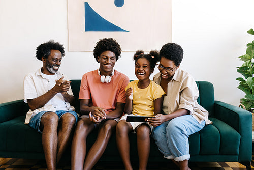 Black Brazilian family laughing happily as they interact with a tablet