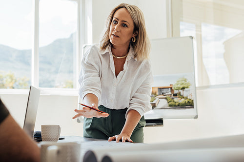 Female architect presenting and discussing design plans with a colleague in office
