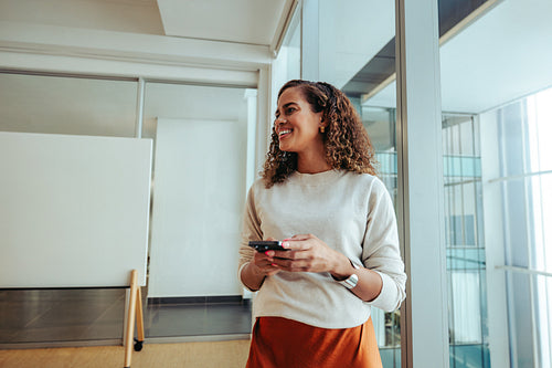 Smiling woman holding a smartphone in a modern office studio