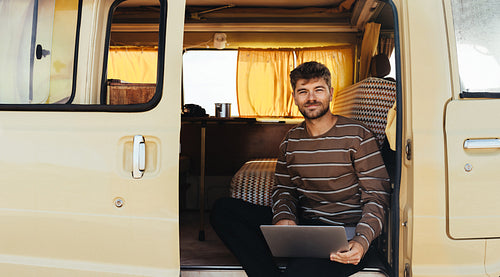 Man works on laptop inside vintage van during travel