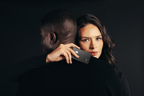 Embracing an exclusive cashless consumerism: Woman hugging a man with a credit card in her hand