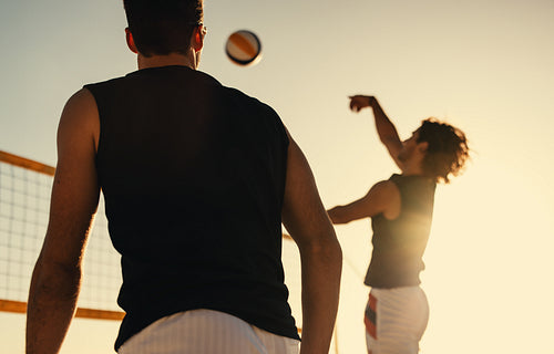 Dynamic beach volleyball tournament: Athletes spiking and blocking in sunset sky