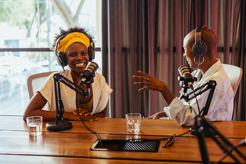 Two happy podcast hosts engaged in a lively conversation in a studio setting