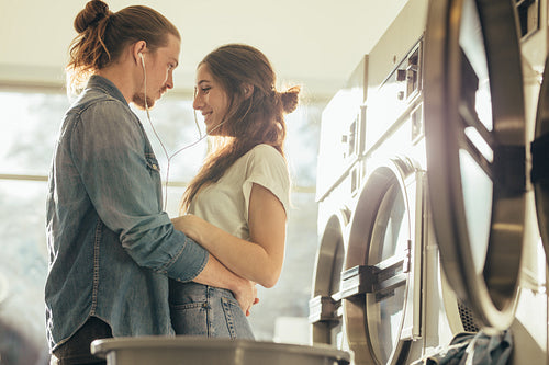 Couple in love standing together listening to music in laundry room