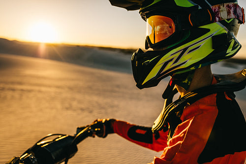 Motocross biker sitting on his racing bike in a desert