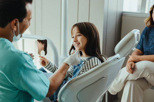 Child smiles with mirror during dental clinic visit with parent support
